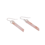 A pair of pale pink hook earrings placed on a white surface.